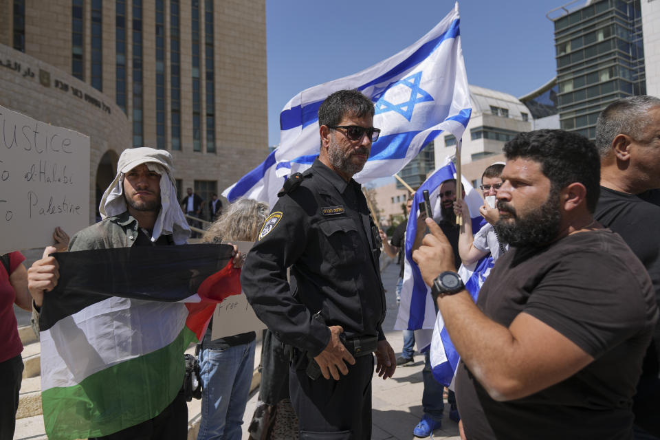 Supporters of Mohammed el-Halabi hold a Palestinian flag and placards as protesters wave Israeli flags, outside the district court in the southern Israeli city of Beersheba, Wednesday, June 15, 2022. The court found the Gaza aid worker guilty of several terrorism charges. El-Halabi, who was the Gaza director for the Christian charity World Vision from 2014 until his arrest in 2016, was accused of diverting tens of millions of dollars to the Islamic militant group Hamas that rules the territory. Both el-Halabi and World Vision have denied any wrongdoing, and an independent audit in 2017 also found no evidence of support for Hamas. (AP Photo/Tsafrir Abayov)