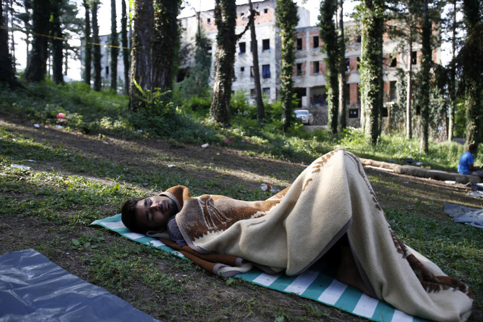 In this photo taken on Tuesday, Aug. 14, 2018, a migrant man sleeps on the ground a makeshift migrant camp in Bihac, 450 kms northwest of Sarajevo, Bosnia. Impoverished Bosnia must race against time to secure proper shelters for at least 4,000 migrants and refugees expected to be stranded in its territory during coming winter. The migrant trail shifted toward Bosnia as other migration routes to Western Europe from the Balkans were closed off over the past year. (AP Photo/Amel Emric)