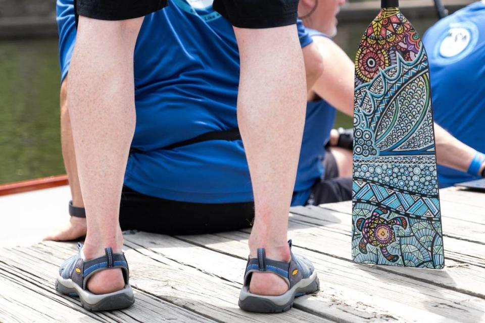 A SLAP Dragons team member waits to board a boat with a bright paisley patterned oar during the 35th annual Kansas City Dragon Boat Festival.