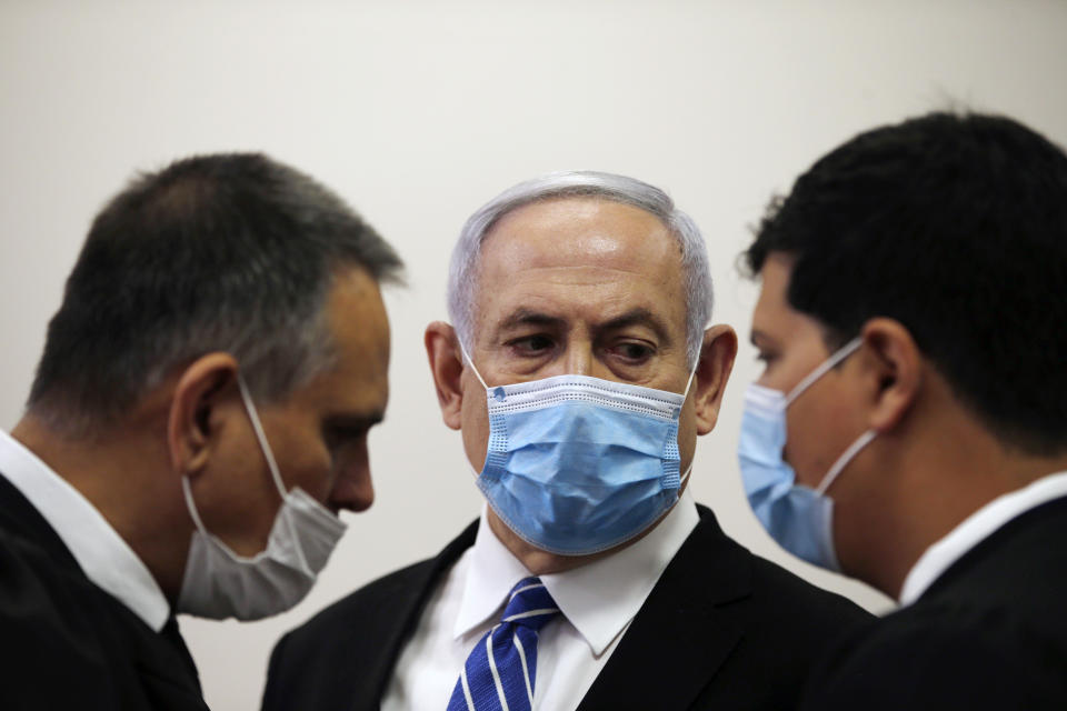 Israeli Prime Minister Benjamin Netanyahu, wearing a face mask in line with public health restrictions due to the coronavirus pandemic, looks at his lawyer inside the court room as his corruption trial opens at the Jerusalem District Court, Sunday, May 24, 2020. He is the country’s first sitting prime minister ever to go on trial, facing charges of fraud, breach of trust, and accepting bribes in a series of corruption cases stemming from ties to wealthy friends. (Ronen Zvulun/ Pool Photo via AP)
