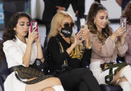 Cristy Solis, wife of singer Marco Antonio Solis, center, and their daughters Alison Solis, left, and Marla Solis take photos as they attend a press conference for Mexican grupera band Los Bukis at SoFi Stadium on Monday, June 14, 2021, in Inglewood, Calif. Twenty five years after their last show as a band, Los Bukis announced that they are reuniting for a U.S. tour. (AP Photo/Chris Pizzello)