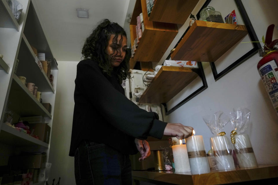 A woman lights candles in her store after a programed power cut ordered by the ministry of energy, in Quito, Ecuador, Tuesday, April 16, 2024. Ecuador faces electricity rationing due to a prolonged drought and high temperatures that have reduced flows to the main hydroelectric plants. (AP Photo/Dolores Ochoa)