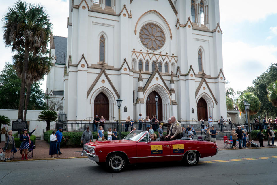 Chatham County Sheriff John Wilcher drives by the Cathedral of St. John the Baptist while onlookers wave at the parade from seats in front.