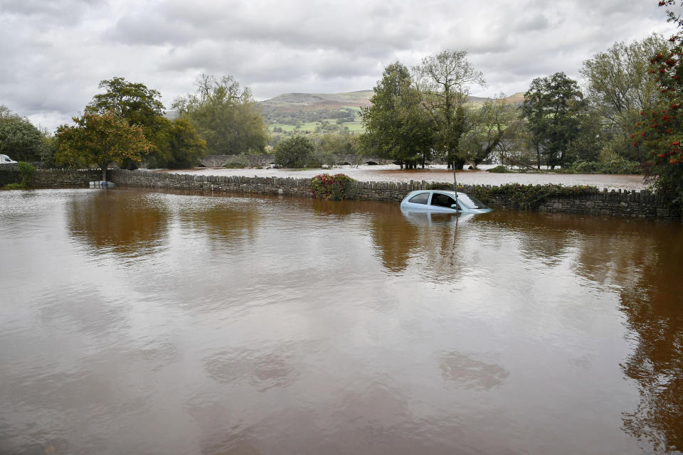 A stranded vehicle parked in flood water in a car park next to the A4077 where an amber weather warning is in force across the region as heavy rain is causing flooding, in Crickhowell, Wales, Saturday, Oct. 13, 2018. (Ben Birchall/PA via AP)