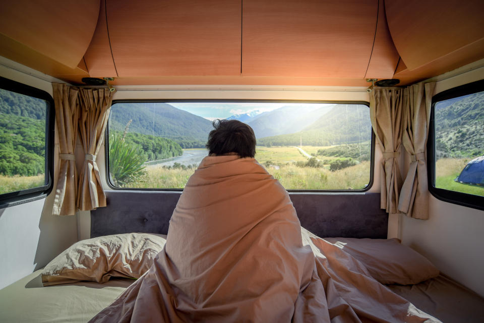 A man sitting in an RV looking out onto a mountainous landscape