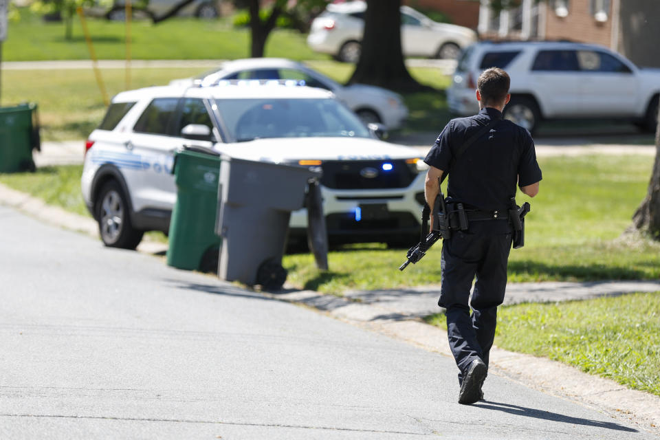 A Charlotte Mecklenburg police officer walks carrying a gun in the neighborhood where a shooting took place in Charlotte, N.C., Monday, April 29, 2024. The Charlotte-Mecklenburg Police Department says officers from the U.S. Marshals Task Force were carrying out an investigation Monday afternoon in a suburban neighborhood when they came under gunfire. (AP Photo/Nell Redmond)