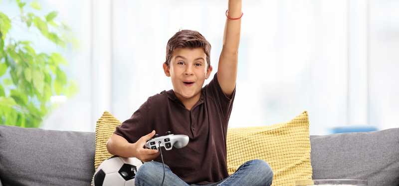 A boy sits on a couch an uses a video game controller.