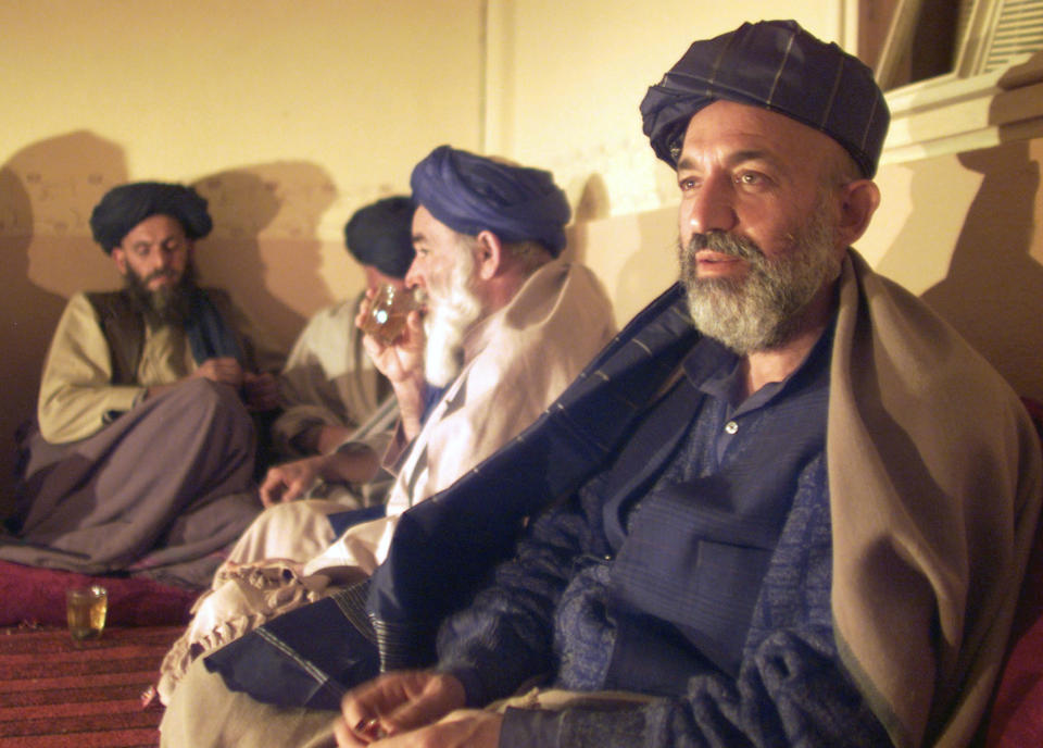 FILE - Hamid Karzai, Afghanistan's interim prime minister, right, meets with tribal leaders from the five southern Afghan states in the house where Taliban supreme leader Mullah Mohammed Omar used to live in Kandahar, Afghanistan, Monday, Dec. 10, 2001. The former Soviet Union marched into Afghanistan on Christmas Eve, 1979, claiming it was invited by the new Afghan communist leader, Babrak Karmal, setting the country on a path of 40 years of seemingly endless wars and conflict. After the Soviets left in humiliation, America was the next great power to wade in. (AP Photo/Jerome Delay)