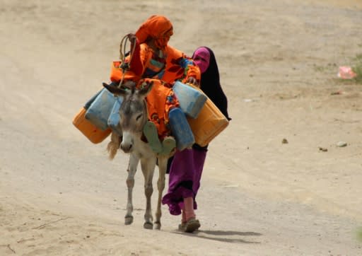 Yemeni children displaced from the Red Sea port city of Hodeida walk with a donkey to fill up their jerry-cans with water, at a camp for the displaced