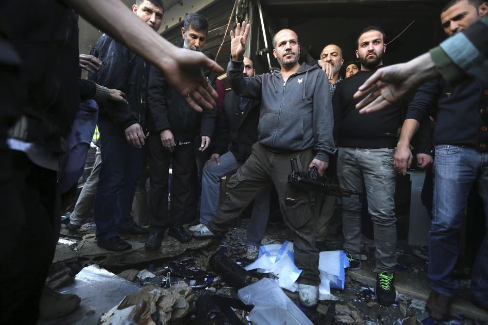 Civilians and Hezbollah members stand at the site of an explosion in the Haret Hreik area, in the southern suburbs of the Lebanese capital Beirut