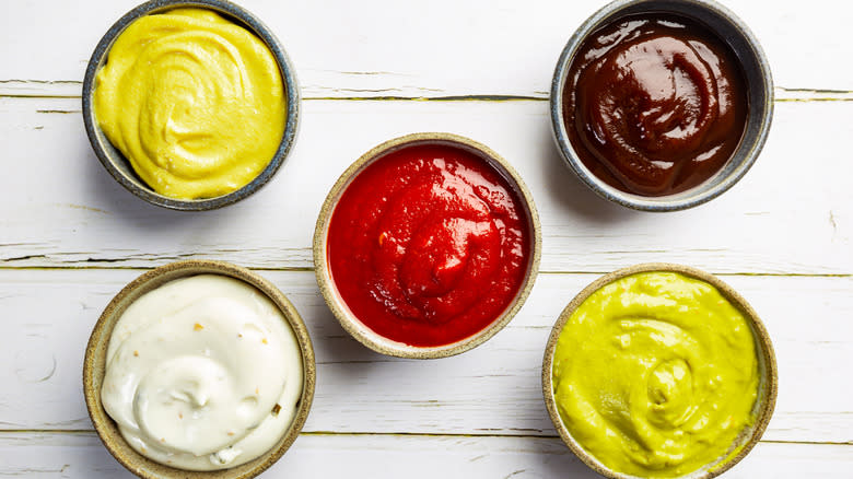 five pots of brightly colored condiments