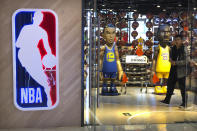 A man walks past statues of NBA players Stephen Curry of the Golden State Warriors, left, and Lebron James of the Los Angeles Lakers holding Chinese flags in the entrance of an NBA merchandise store in Beijing, Tuesday, Oct. 8, 2019. Chinese state broadcaster CCTV announced Tuesday it will no longer air two NBA preseason games set to be played in the country. (AP Photo/Mark Schiefelbein)