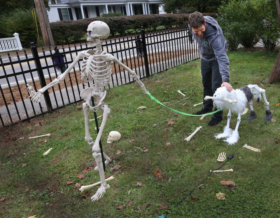 Aaron Berlin pats a fake dog being led by a skeleton as part of Halloween decorations set up by him and his family on Summer Street in Kennebunk.