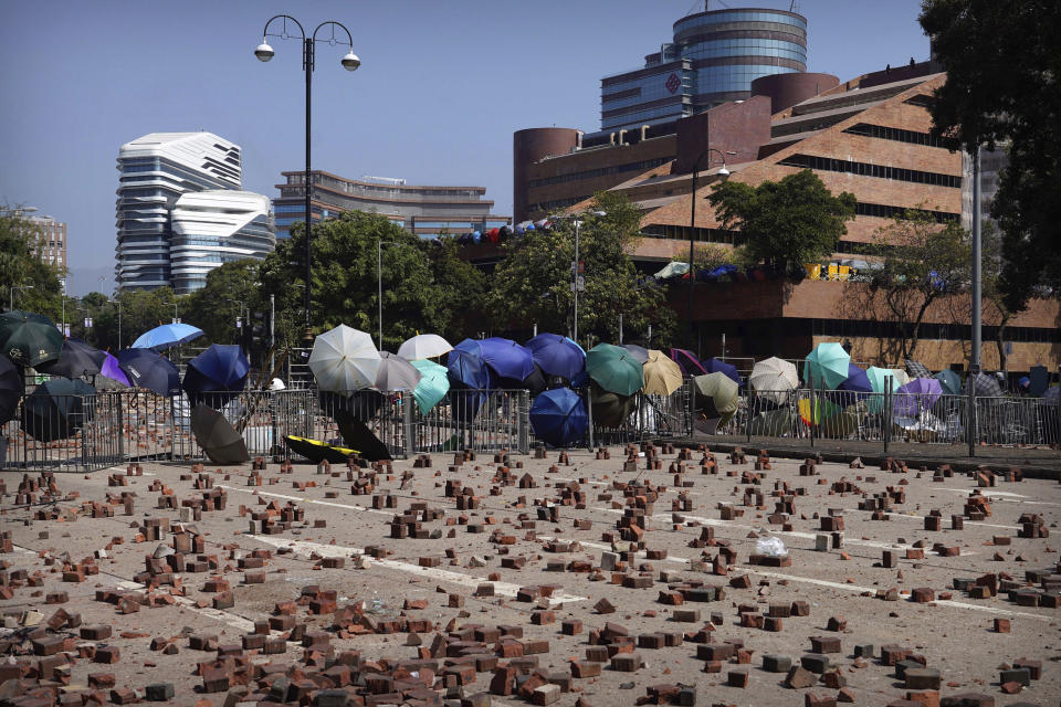 Bricks are scattered on a road in front of a barricade built by protesters at Hong Kong Polytechnic University in Hong Kong, Friday, Nov. 15, 2019. Protesters who have barricaded themselves in a Hong Kong university partially cleared a road they were blocking and demanded that the government commit to holding local elections on Nov. 24. (AP Photo/Vincent Yu)