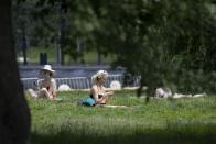 FILE - In this Thursday, June 18, 2020 file photo, people sit on the grass in Gorky Park in Moscow, Russia during a heat wave. An overheating world obliterated weather records in 2020 — an extreme year for hurricanes, wildfires, heat waves, floods, droughts and ice melt — the United Nations’ weather agency reported Wednesday, Dec. 2, 2020. (AP Photo/Alexander Zemlianichenko)