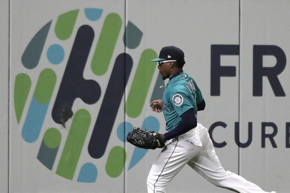 Seattle Mariners left fielder Shed Long runs next to a graphic on the outfield wall after catching a line-out by Oakland Athletics' Marcus Semien during the sixth inning of a baseball game, Friday, Sept. 27, 2019, in Seattle. (AP Photo/Ted S. Warren)