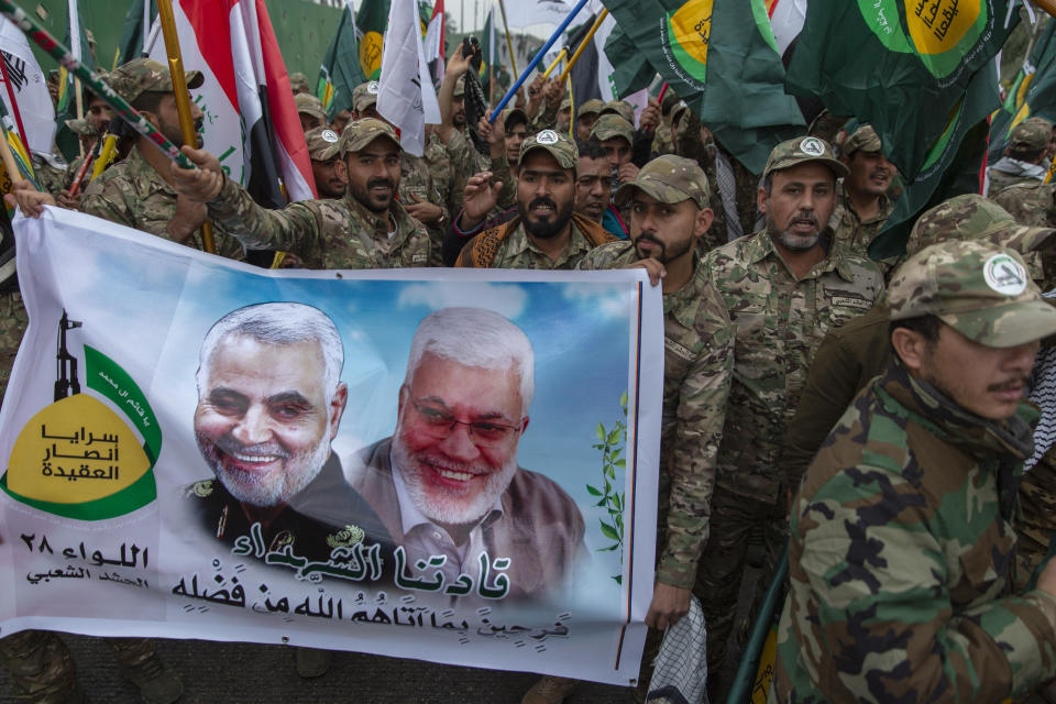 FILE - In this Saturday, Jan. 4, 2020 file photo, Iraqi militiamen march and chant anti U.S. slogans while carrying a picture of Soleimani, left and al-Muhandis, with Arabic that reads "our martyr leaders," during the funeral of Iran's top general Qassem Soleimani and Abu Mahdi al-Muhandis, deputy commander of Iran-backed militias in Iraq known as the Popular Mobilization Forces, in Baghdad, Iraq. Iraqi militia leaders were expecting the usual bags of cash when the new head of Iran's expeditionary Quds Force , a successor Soleimani, paid his first visit. Instead, Esmail Ghani brought them silver rings, as tokens of gratitude. The episode, relayed by several officials, illustrates Iran's struggle to maintain influence abroad as it grapples with the economic fallout from crushing U.S. sanctions and the coronavirus. (AP Photo/Nasser Nasser, File)