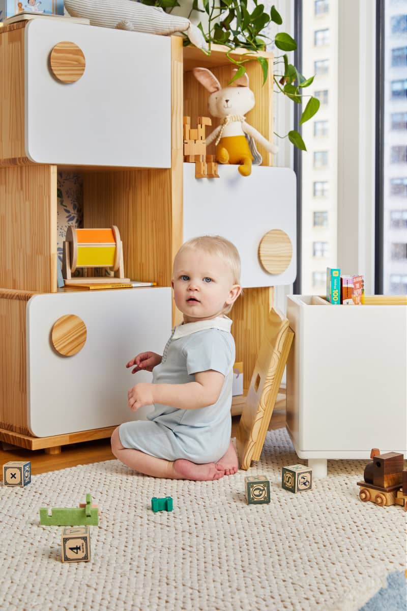 Baby playing with toys in nursery.