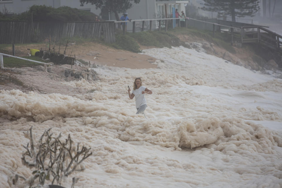 A woman in the middle of surging sea foam at Collaroy. Source: Getty/Brook Mitchell