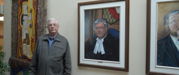 David Searle, seen here in the N.W.T. Legislature in July 2018, standing beside his Speakers portrait. (Submitted by Katie Weaver - image credit)