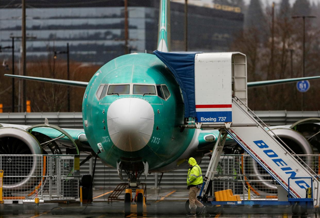 FILE PHOTO: An employee walks past a Boeing 737 Max aircraft seen parked at the Renton Municipal Airport in Renton, Washington, U.S. January 10, 2020. REUTERS/Lindsey Wasson