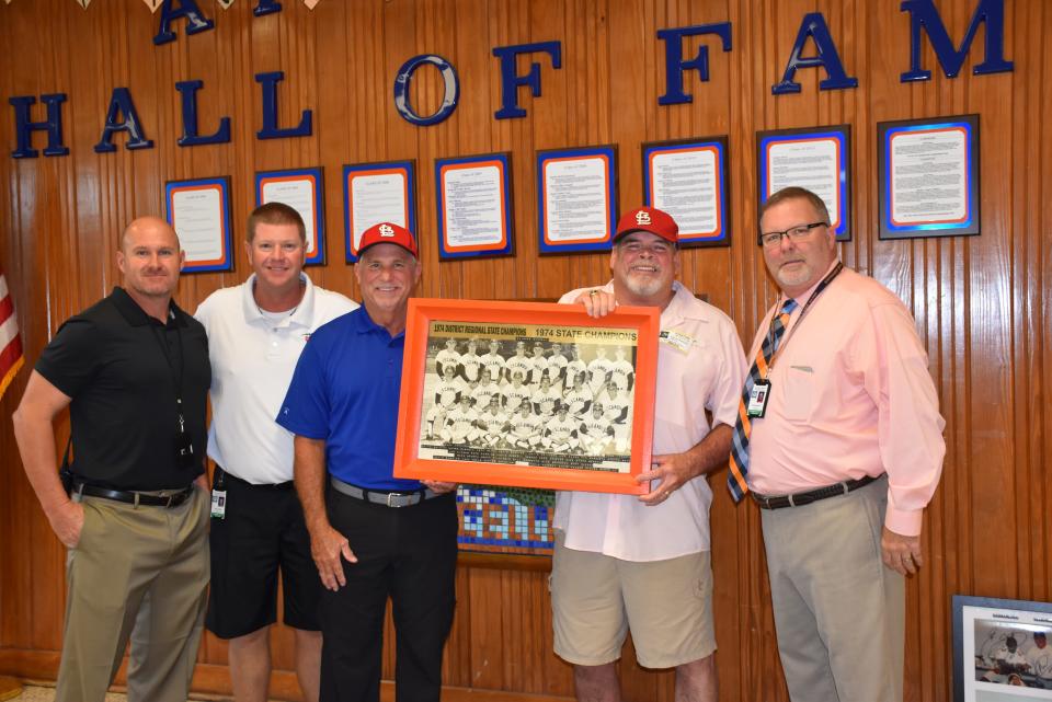 Kevin Morrell (blue shirt) and Kevin Saucier, both members of the 1974 Escambia High state baseball championship team, donated more than 50 pairs expensive new cleats to the program. EHS baseball coach Tracey King, far left, athletic director Ryan James, and EHS principal Frank Murphy joined in presentation.