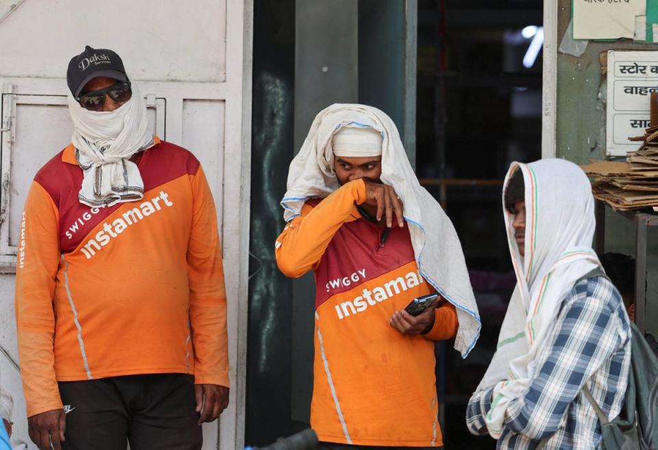 A delivery partner with the Indian online delivery company Swiggy wipes sweat off his face as he waits outside with other delivery partners at one of Swiggy’s Instamart dark stores on a hot summer day, during a heatwave in New Delhi (Reuters)