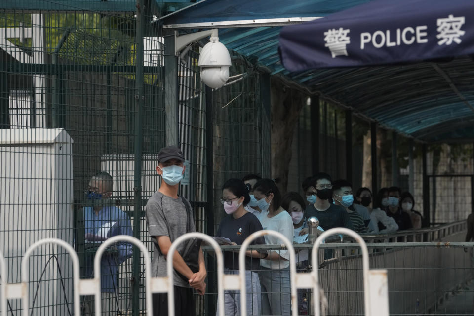 A plain clothes security person stands guard as visitors to the U.S. consular service line up outside the U.S. embassy in Beijing, Monday, Aug. 1, 2022. U.S. House Speaker Nancy Pelosi has arrived in Singapore, kicking off her Asian tour as questions swirled over a possible stop in Taiwan that has fueled tension with Beijing. (AP Photo/Ng Han Guan)