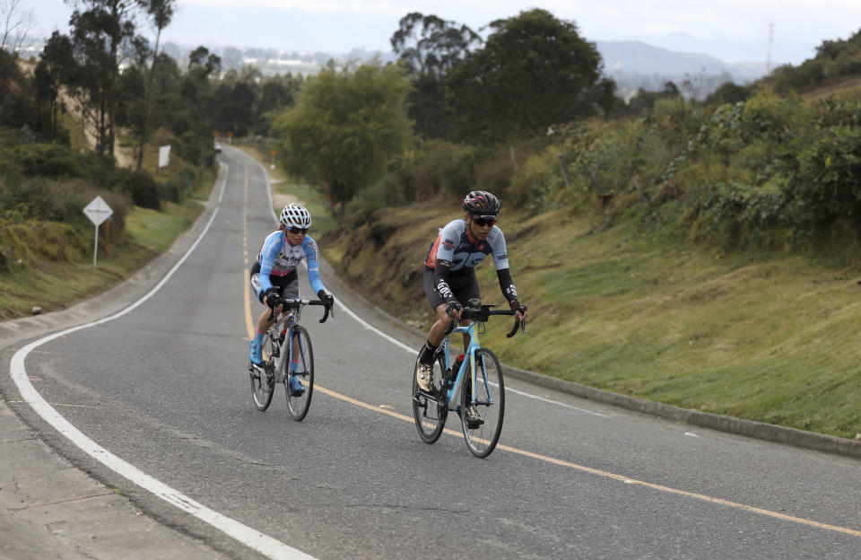 Former professional cyclist Armando Cardenas, right, trains as he rides from the town of Madrid to Zipacon, Colombia, Tuesday, Aug. 27, 2019. When Cardenas raced professionally, like many of his fellow Colombian cyclists, he made the decision to dope. "I wanted to know what it meant to race while doping," says Cardenas, who now coaches a crop of local talent, "and the difference was huge." (AP Photo/Fernando Vergara)