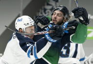 Winnipeg Jets defenseman Dylan DeMelo (2) fights for control of the puck with Vancouver Canucks center Zack MacEwen (71) during second-period NHL hockey game action in Vancouver, British Columbia, Sunday, Feb. 21, 2021. (Jonathan Hayward/The Canadian Press via AP)