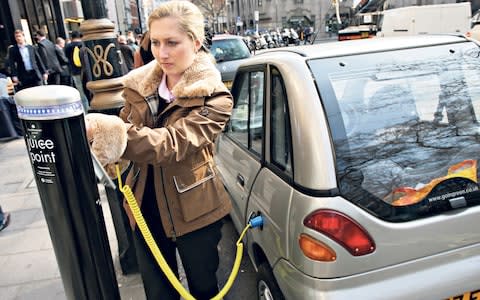 B98E0N Woman charging electric vehicle, Westminster, London, UK. Andrew Butterton / Alamy - Credit: Andrew Butterton/Alamy