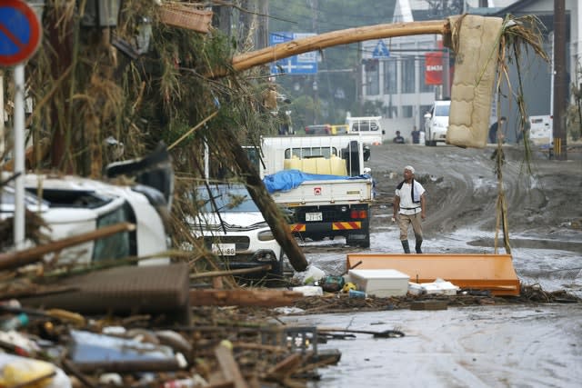 A man stands watch as debris and mud flown in a road in Hitoyoshi (Takuto Kaneka/AP)