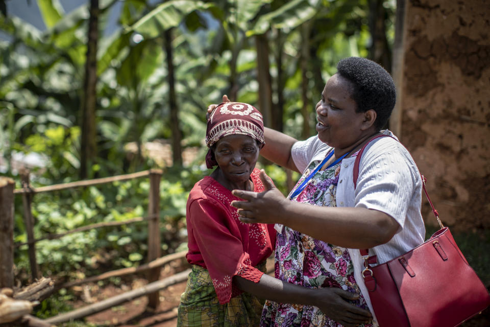 In this photo taken Tuesday, Nov. 5, 2019, palliative care nurse Madeleine Mukantagara, 56, right, is hugged by Josephine Kabagwire, left, whose sister-in-law Vestine Uwizeyimana, 22, has spinal degenerative disease and is taking oral liquid morphine for her pain, after a visit to check on her health at her home in the village of Bushekeli, near Kibogora, in western Rwanda. While people in rich countries are dying from overuse of prescription painkillers, people in Rwanda and other poor countries are suffering from a lack of them, but Rwanda has come up with a solution to its pain crisis - it's morphine, which costs just pennies to produce and is delivered to households across the country by public health workers. (AP Photo/Ben Curtis)