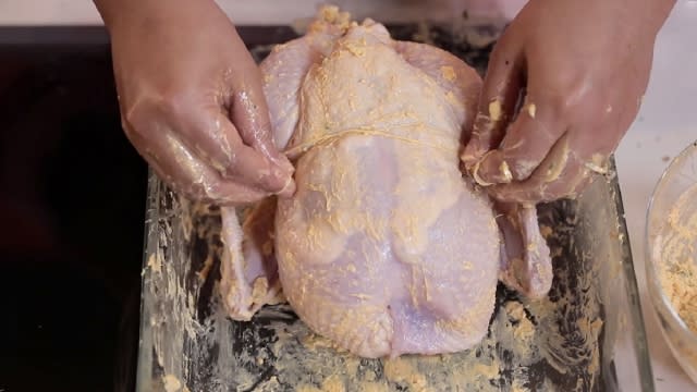 using a kitchen tool to tie up chicken legs and wings