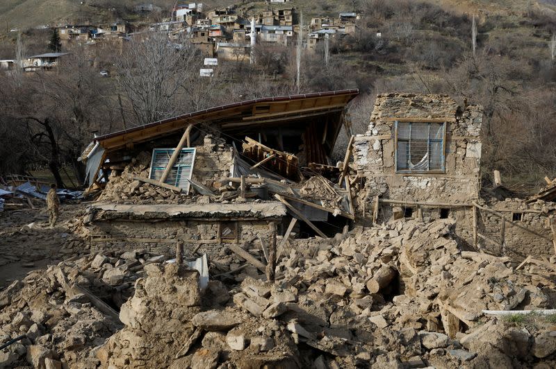 A person stands next to a damaged house, after an earthquake in Cevrimtas