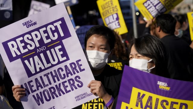 Medical workers and supporters carry signs and march as they protest outside of a Kaiser Permanente facility.