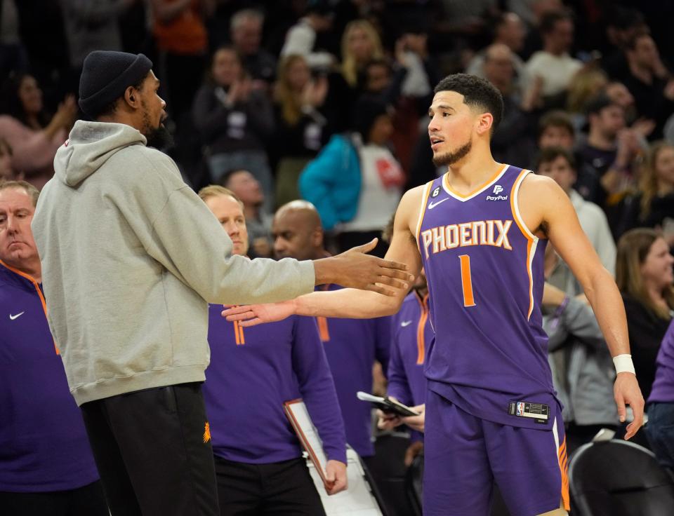 Feb 14, 2023; Phoenix, Ariz., U.S;  Phoenix Suns forward Kevin Durant slaps hands with guard Devin Booker (1) during the fourth quarter against the Sacramento Kings at Footprint Center.