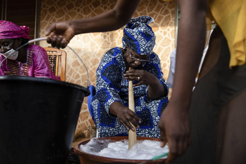 Women gather to make soap at Zenabou Coulibaly Zongo's house in Ouagadougou, Burkina Faso, Tuesday, Oct. 26, 2021. Zongo spends her own money making soap and buying hand sanitizer for mosques, markets and health centers. At the start of the pandemic, Zongo, now 63, was hospitalized with bronchial pneumonia. She paid out of pocket for two weeks' worth of oxygen treatments at a private clinic, where she watched others die from respiratory problems. (AP Photo/Sophie Garcia)