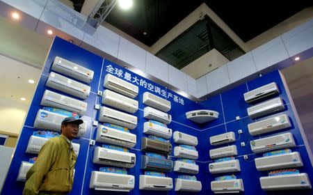 A man inspects China-made air-conditioners on display at a home appliance exhibition in Beijing May 9, 2004. The Chinese characters on the wall reads "The world's biggest air-condition produce base". REUTERS/Wilson Chu/Files