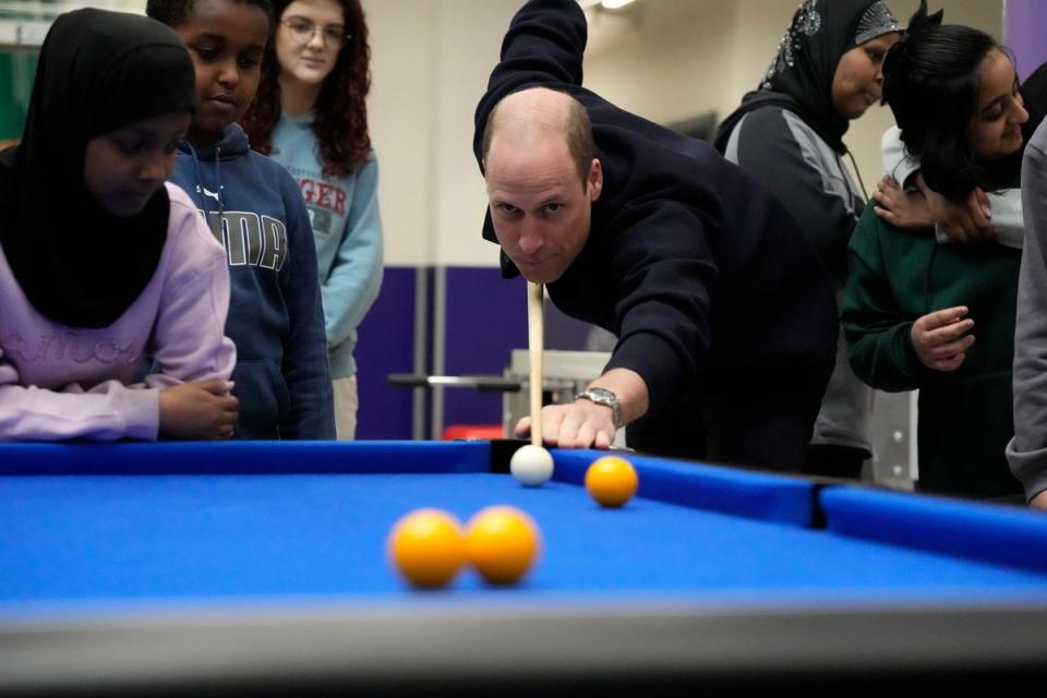 Prince William plays a game of pool during his visit (AP)