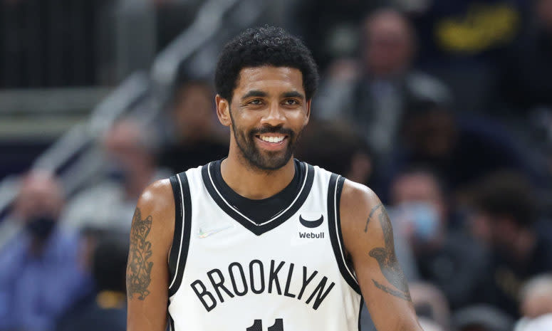 Kyrie Irving smiling while dribbling the ball up the court.