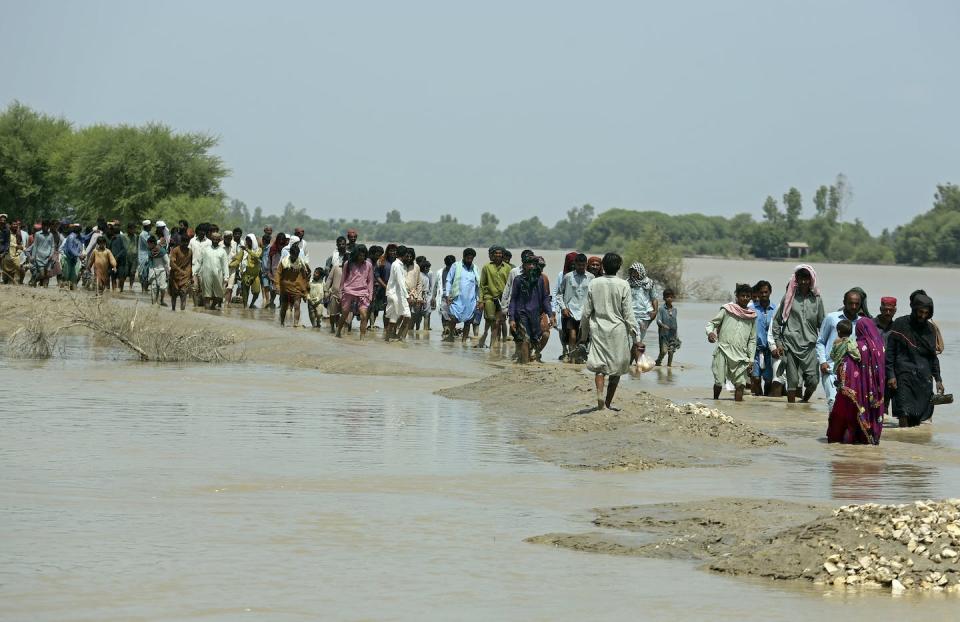 People walk through flood waters to receive aid in Pakistan, Sept. 7, 2022. Despite a disaster management authority at the federal and provincial levels, disaster preparedness has not been prioritized. (AP Photo/Fareed Khan)