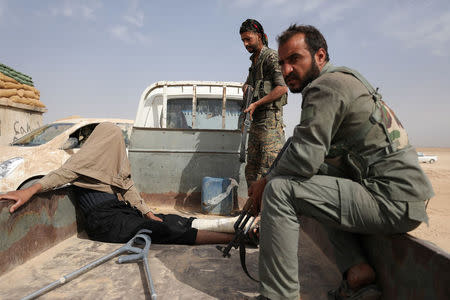 Fighters from Syrian Democratic Forces (SDF) are seen after arresting a wounded man during their fighting with Islamic State in the northern area of Deir al-Zor, Syria September 24,2017. REUTERS/ Rodi Said