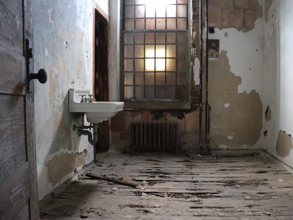 an empty room in ellis island hospital with peeling paint a sink