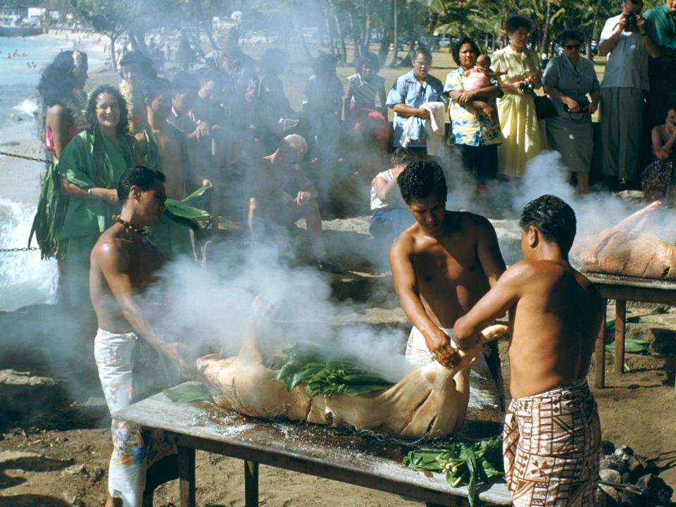 Men prepare a Kalua Pig for a luau in Hawaii, USA, circa 1960.