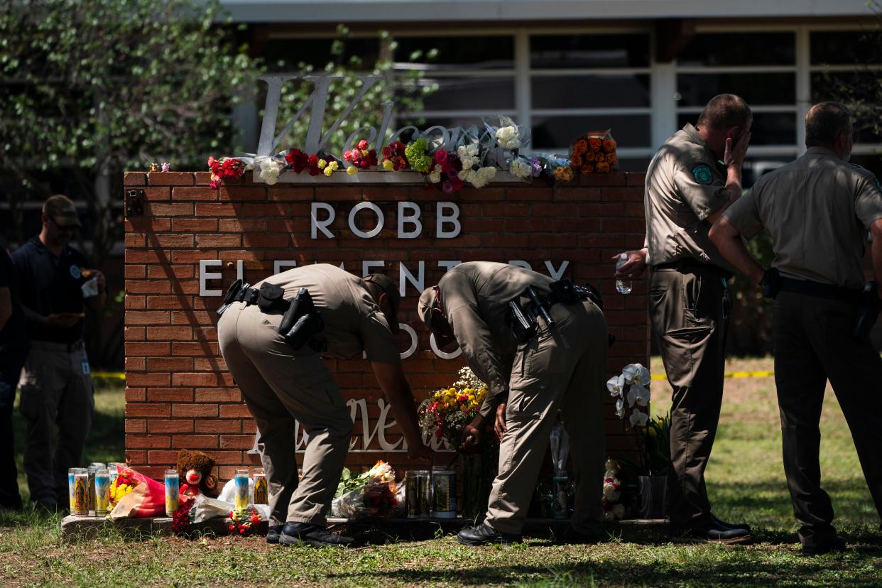 Two Texas Troopers light a candle at Robb Elementary School in Uvalde, Texas, on Wednesday.