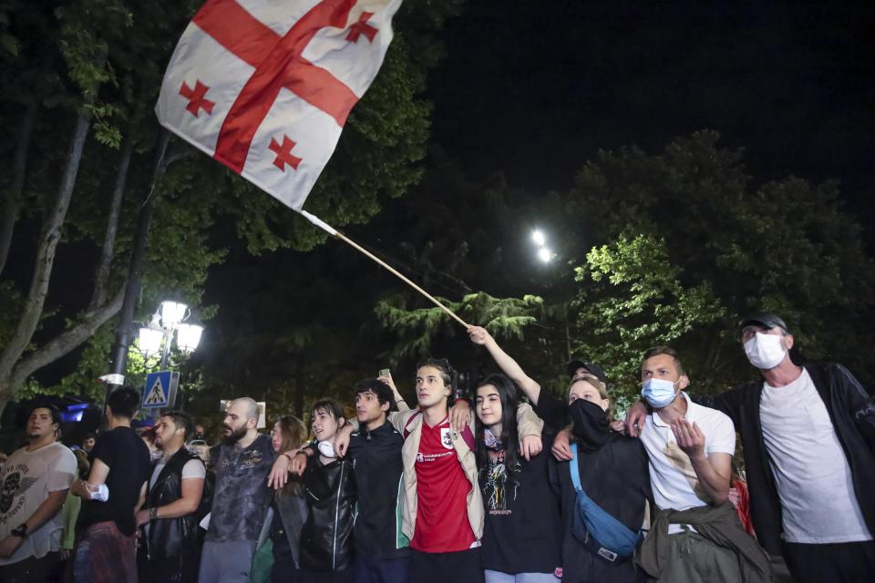 Demonstrators wave a Georgian national flag standing in front of police block during an opposition protest against a bill near the Parliament building in Tbilisi, Georgia, on Thursday, May 2, 2024. Protesters denounce the bill as "the Russian law" because Moscow uses similar legislation to stigmatize independent news media and organizations critical of the Kremlin. (AP Photo/Zurab Tsertsvadze)