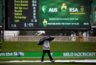 Cricket - Australia v South Africa - Second Test cricket match - Bellerive Oval, Hobart, Australia - 13/11/16 Umpire Mick Martell holds an umbrella while walking around the covered pitch as rain falls during the second day of the second test between Australia and South Africa. REUTERS/David Gray