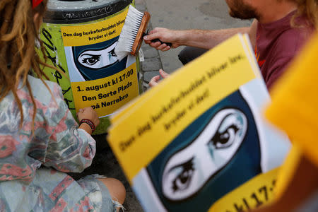 Members of the activist group Party Rebels, paste up posters alerting people to an organised protest against the face veil ban in Copenhagen, Denmark, July 23, 2018. REUTERS/Andrew Kelly