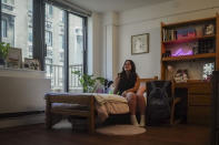 Sara Hunt, 19, a sophomore at New York University from Pigeon Forge, Tennessee, sits in her dorm room, Wednesday, Aug. 30, 2023, in New York. Hunt wanted her dorm room to look cozy but her budget was $100. She decorated her room with plants, mementos, and pillows covered with images of her pets. (AP Photo/Bebeto Matthews)